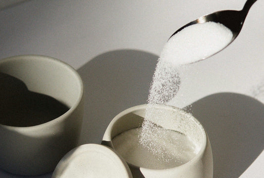Teaspoon pouring sugar into cup